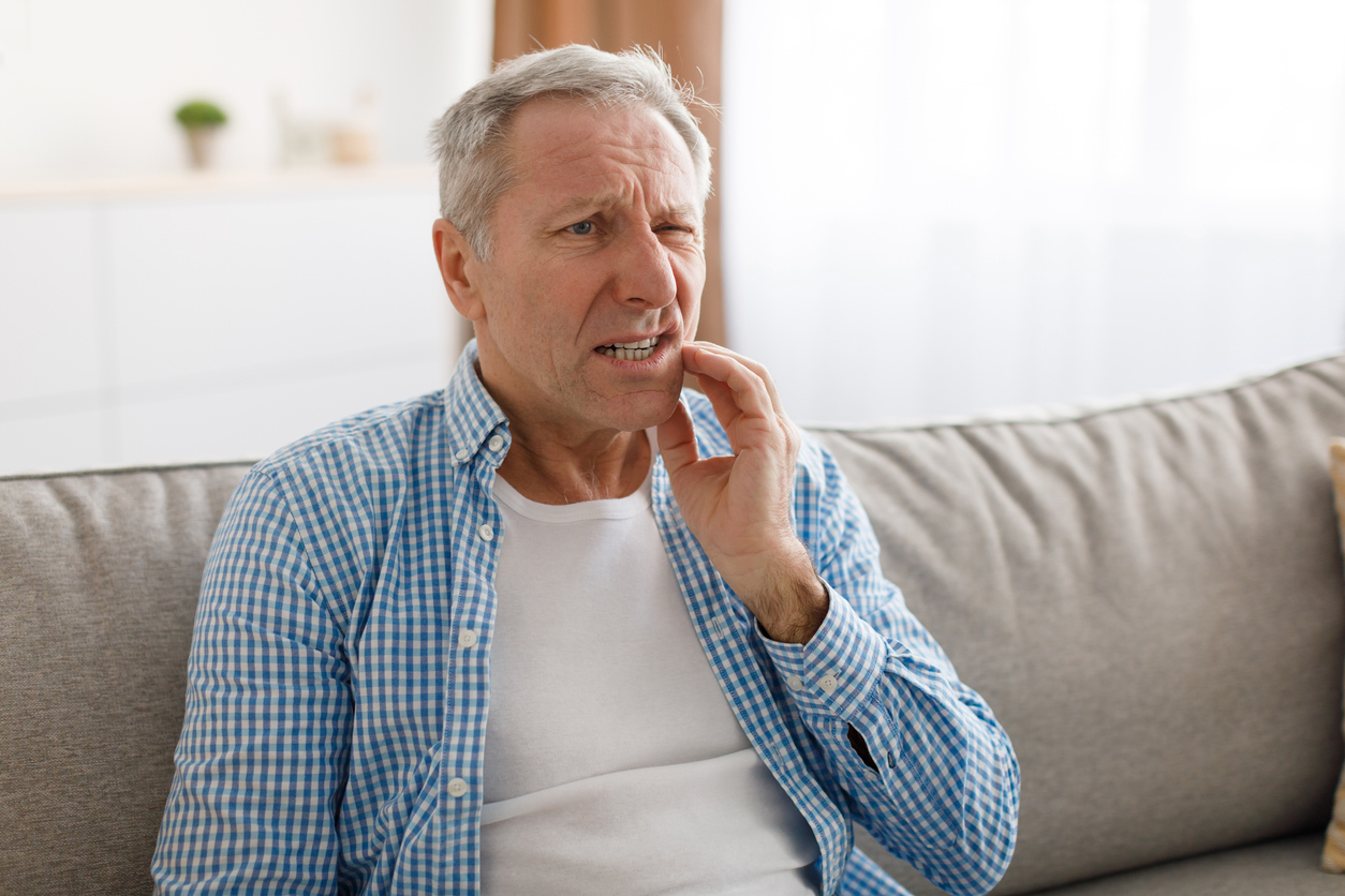 Portrait of unhappy mature man suffering from toothache, before visiting emergency dentist